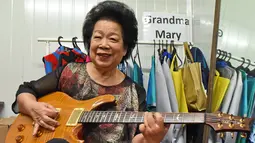 Mary Ho (81) berpose dengan gitar elektriknya saat melakukan latihan di Singapura, 5 Agustus 2017. Wanita yang dikenal sebagai Nenek Maria itu baru belajar gitar pada usia 60 tahun setelah sejak lama memimpikan belajar alat musik ini. (Roslan RAHMAN/AFP)