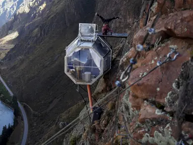 Seorang tamu melakukan yoga di atas kapsul tidur di Skylodge Adventure Suites di Lembah Suci di Cuzco, Peru, 14 Agustus 2015. Hotel yang tergantung dengan ketinggian 400 meter ini memiliki tarif sekitar Rp 4 juta per malam. (REUTERS/Pilar Olivares)