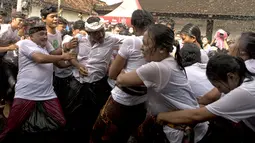 Seorang pria mencoba memeluk seorang wanita selama tradisi Omed-omedan (cium-ciuman) di Denpasar, Bali, Jumat (4/3/2022). "Omed-omedan" merupakan ritual tradisi khas muda-mudi yang dilaksanakan sehari setelah Hari Raya Nyepi. (AP Photo/Firdia Lisnawati)