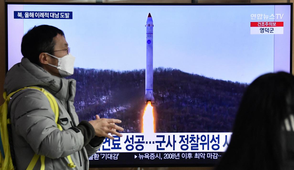 Seorang pria berjalan melewati layar televisi yang menayangkan siaran berita dengan rekaman file uji coba rudal Korea Utara, di sebuah stasiun kereta api di Seoul, Sabtu (31/12/20220). Otoritas Pyongyang belum memberikan pernyataan resmi terkait peluncuran terbaru tersebut. (Jung Yeon-je / AFP)
