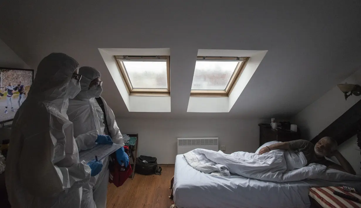 Petugas kesehatan menggunakan APD berbincang dengan tunawisma pasien virus corona di kamar hotel di Praha, Senin (8/3/2021). Di hotel berbintang empat King Charles Boutique, paramedis merawat dan memberikan obat kepada para tunawisma yang terpapar Covid-19. (MICHAL CIZEK/AFP)