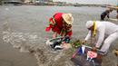 Dukun Peru mencuci poster Presiden Terpilih AS Donald Trump dan Presiden Rusia, Vladimir Putrin saat menggelar ritual di Pantai Agua Dulce di Lima, Peru, (29/12). Dukun tersebut juga meramalkan banyaknya serangan teroris di Eropa. (Reuters/Mariana Bazo)