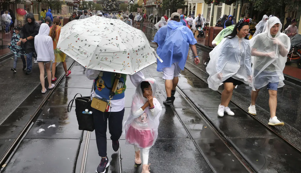 Pengunjung menantang cuaca saat kondisi memburuk dengan mendekatnya Badai Nicole ke kawasan Walt Disney World di Lake Buena Vista, Florida, Rabu (9/11/2022). Semua taman Disney di Florida Tengah ditutup Rabu pagi karena badai yang akan datang. (Joe Burbank/Orlando Sentinel via AP)