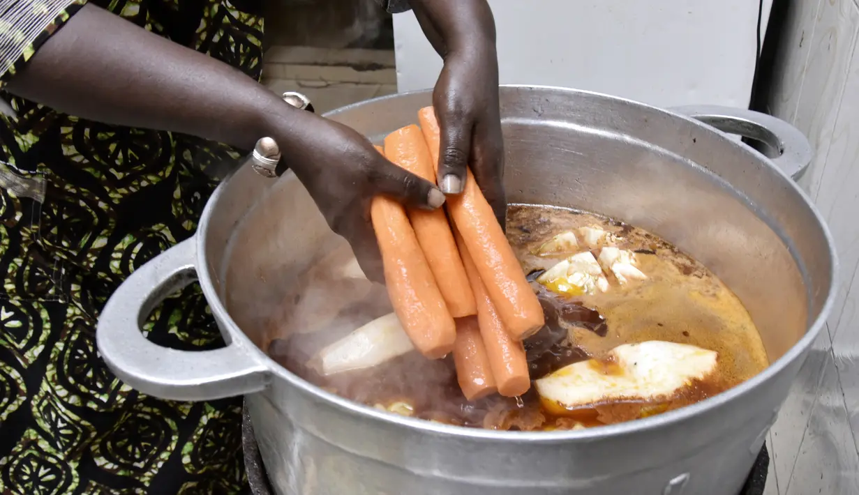 Koki Senegal Thiane Ngom menyiapkan "thiebou dieune" tradisional di rumahnya di Dakar pada 15 Desember 2021. Badan kebudayaan PBB (UNESCO) menambahkan hidangan nasional Senegal, sepiring nasi dengan ikan yang disebut 'thiebou dieune', ke dalam daftar warisan budayanya. (SEYLLOU/AFP)