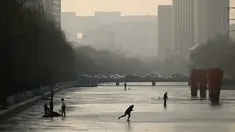 Sejumlah warga bermain ice skating di sungai yang membeku di Beijing, China (10/1). Akibat membeku, Sungai ini menjadi objek wisata dadakan. (AFP Photo/Wang Zhao)