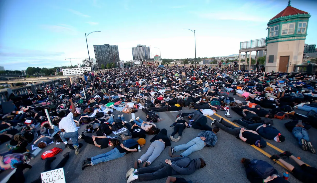 Orang-orang melakukan tiarap di Jembatan Burnside selama sembilan menit saat menyerukan keadilan atas kematian George Floyd di Portland, Oregon, 2 Juni 2020. Aksi menyimbolkan momen terakhir Floyd saat lehernya ditindih lutut polisi Minneapolis pada 25 Mei lalu. (Sean Meagher/The Oregonian via AP)