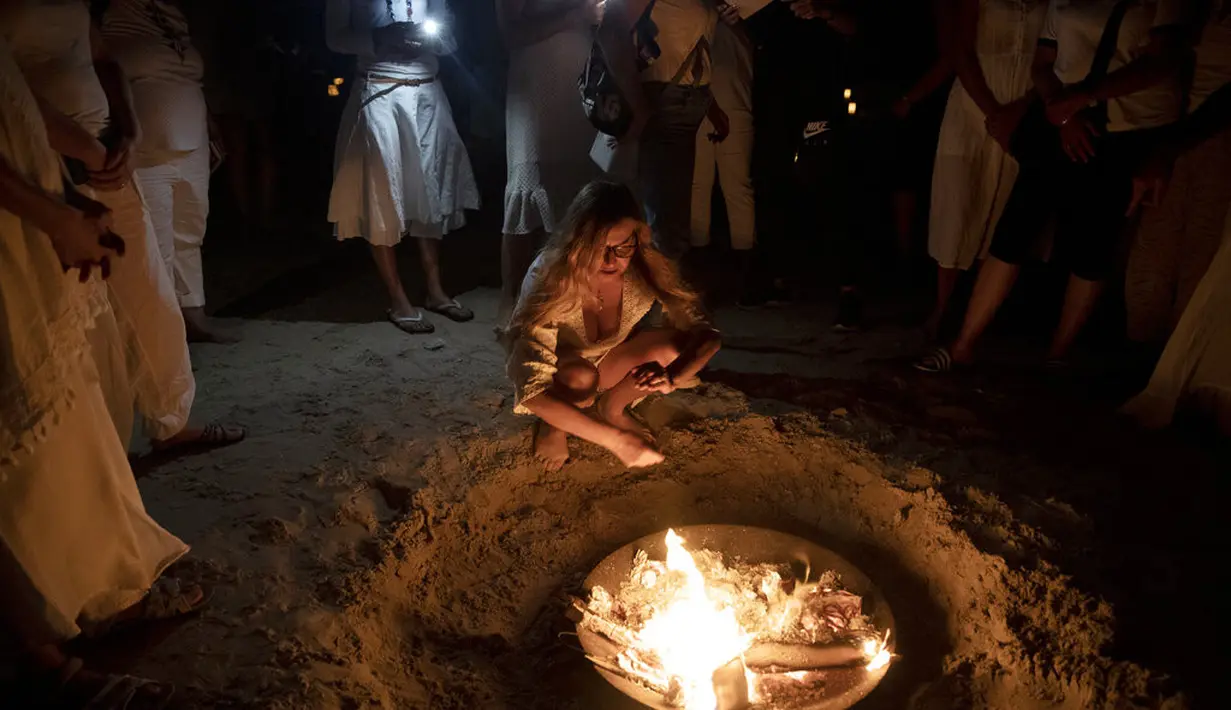 Wanita mengambil bagian dalam upacara Tashlich, di mana mereka menuliskan hal-hal yang ingin mereka lepaskan sebelum melemparkannya ke dalam api, di pantai di Tel Aviv, Israel (14/9/2021). (AP Photo/Maya Alleruzzo)
