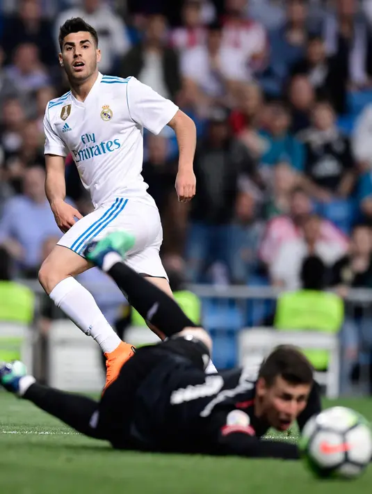 Pemain Real Madrid Marco Asensio berebut bola dengan Kepa Arrizabalaga selama pertandingan La Liga Spanyol di Santiago Bernabeu (18/4). Kepa mengalahkan transfer kiper Liverpool, Alisson Becker (67 juta poundsterling). (AFP Photo/Javier Soriano)