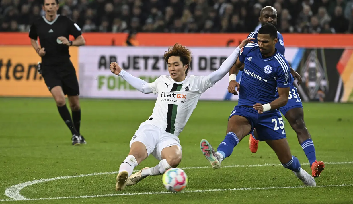Pemain Borussia Monchengladbach, Kou Itakura (kiri) berebut bola dengan pemain Schalke, Moritz Jenz dalam laga Bundesliga 2022/2023 di Borussia-Park, Monchengladbach (4/2/2023). Pemain yang sejak awal musim 2022/2023 membela Borussia Monchengladbach setelah didatangkan dari Manchester City ini kini memiliki nilai pasar senilai 12 juta euro atau setara Rp195 miliar. (dpa via AP Photo/Federico Gambarini)