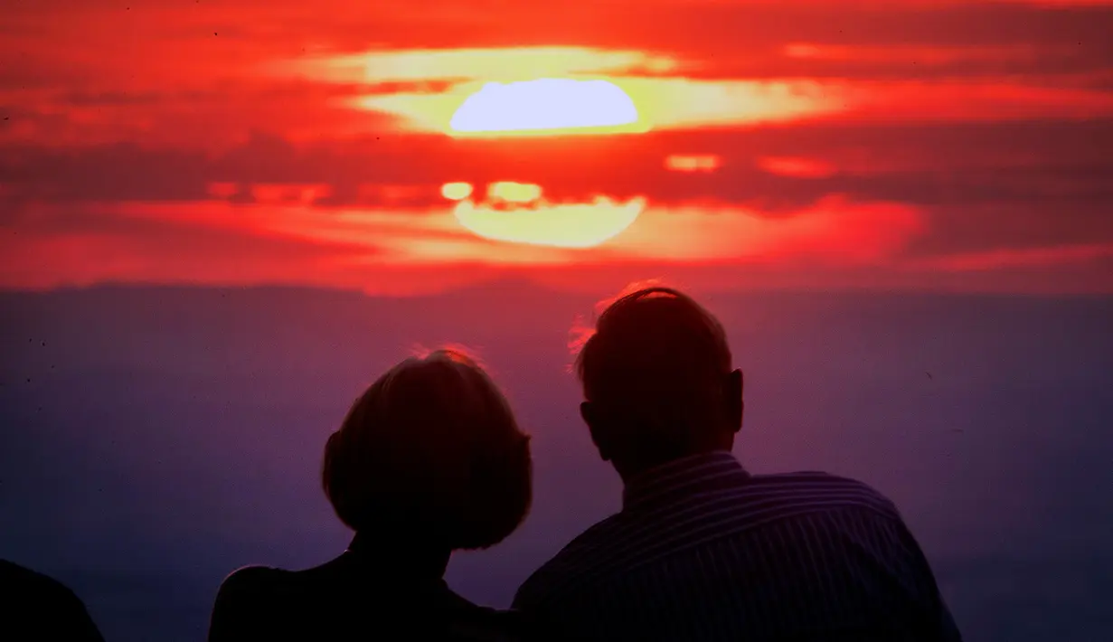 Pasangan melihat matahari terbenam di puncak gunung Feldberg dekat Frankfurt, Jerman,  (30/7). (AP Photo/Michael Probst)