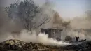 Seorang pria mencoba memadamkan api di daerah kumuh di Noida, pinggiran kota New Delhi, India, Minggu (11/4/2021). Dua anak tewas dan lebih dari 150 gubuk kumuh yang sebagian besar dihuni oleh para pemulung dalam kebakaran pada Minggu sore. (AP Photo/Altaf Qadri)