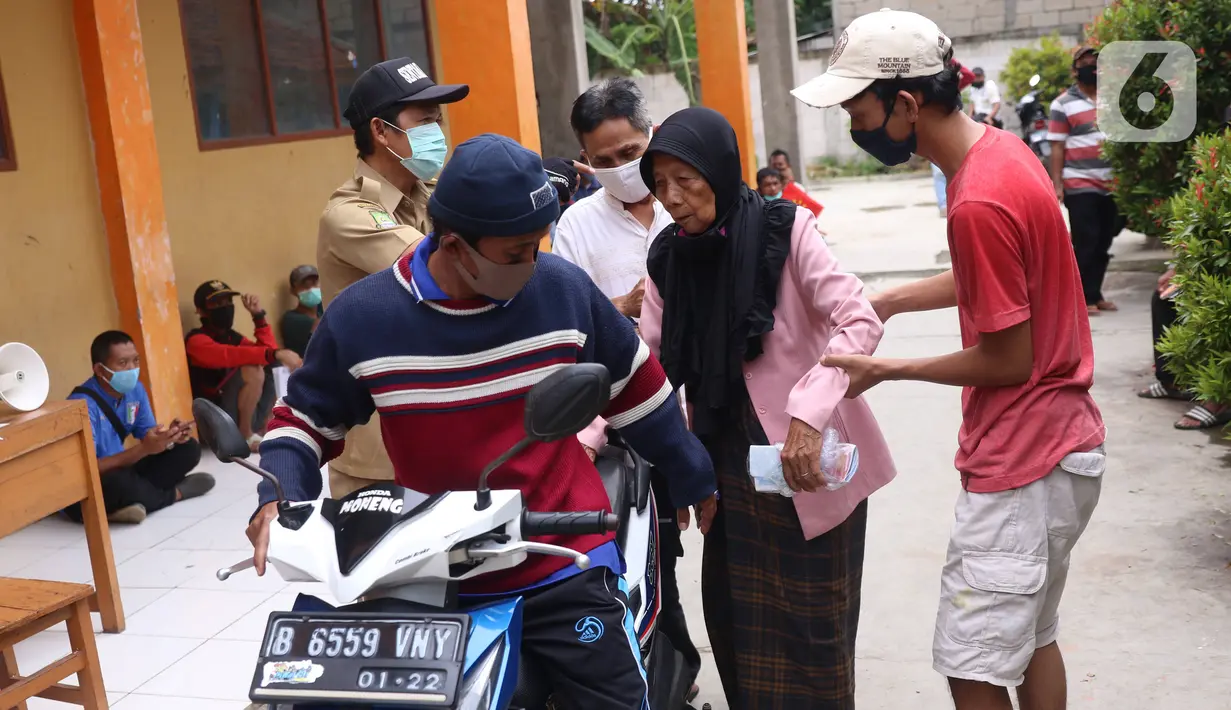 Warga membantu seorang nenek usai mengambil bantuan sosial (bansos) yang diberikan Pemerintah Provinsi Banten di Pinang, Tangerang, Jumat (1/5/2020). Bansos berupa uang tunai sebesar Rp 600 ribu tersebut diberikan kepada warga yang terdampak virus corona COVID-19. (Liputan6.com/Angga Yuniar)