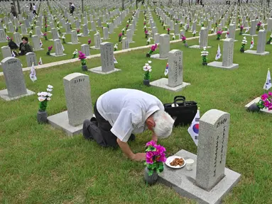 Seorang pria Korsel membungkuk memberi hormat di depan nisan kerabatnya yang gugur untuk negara pada Memorial Day di Pemakaman Nasional Seoul, Kamis (6/6/2019). Memorial Day didedikasikan untuk mengingat prajurit dan warga sipil yang gugur selama perang Korea antara 1950-1953. (Jung Yeon-je/AFP)