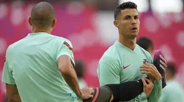 Penyerang Portugal, Cristiano Ronaldo berdiri di samping rekan setimnya Pepe selama sesi latihan di arena stadium di Munich, Jumat (18/6/2021). Portugal akan bertanding melawan Jerman pada grup F Euro 2020 di Allianz Arena. (AP Photo/Matthias Schrader)