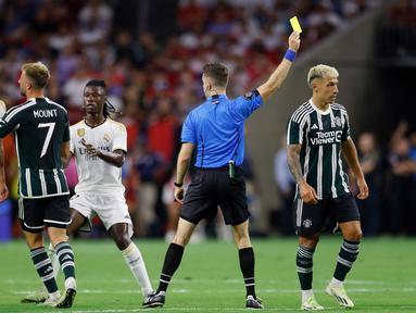 Pemain MU, Lisandro Martinez (kanan), mendapatkan hukuman kartu kuning dari wasit setelah melakukan pelanggaran keras terhadap pemain Real Madrid, Jude Bellingham (kiri), ketika kedua tim bertemu dalam pertandingan pramusim Soccer Champions Tour 2023 yang berlangsung di NRG Stadium, Houston, Kamis (27/7/23). (AFP/Getty Images/Tim Warner)