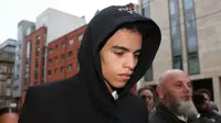 Mason Greenwood mengenakan jas hitam dan kemeja putih di dalamnya sambil menunduk untuk hadir ke persidangan secara singkat.