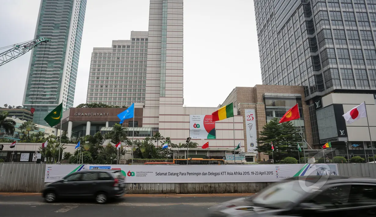 Sejumlah kendaraan melintasi deretan bendera negara peserta Konferensi Asia Afrika ke-60 yang terpasang di dinding proyek MRT kawasan Bundaran HI, Jakarta, Selasa (14/4/2015). (Liputan6.com/Faizal Fanani)