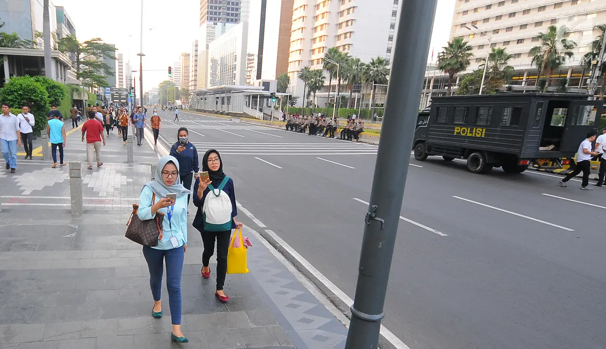 Sejumlah karyawan terpaksa berjalan kaki usai pulang kerja di kawasan Thamrin, Jakarta, Selasa (21/5). Akibat adanya aksi masa tolak hasil pemilu 2019 membuat sejumlah ruas jalan di kawasan tersebut di tutup. (Liputan6.com/Angga Yuniar)