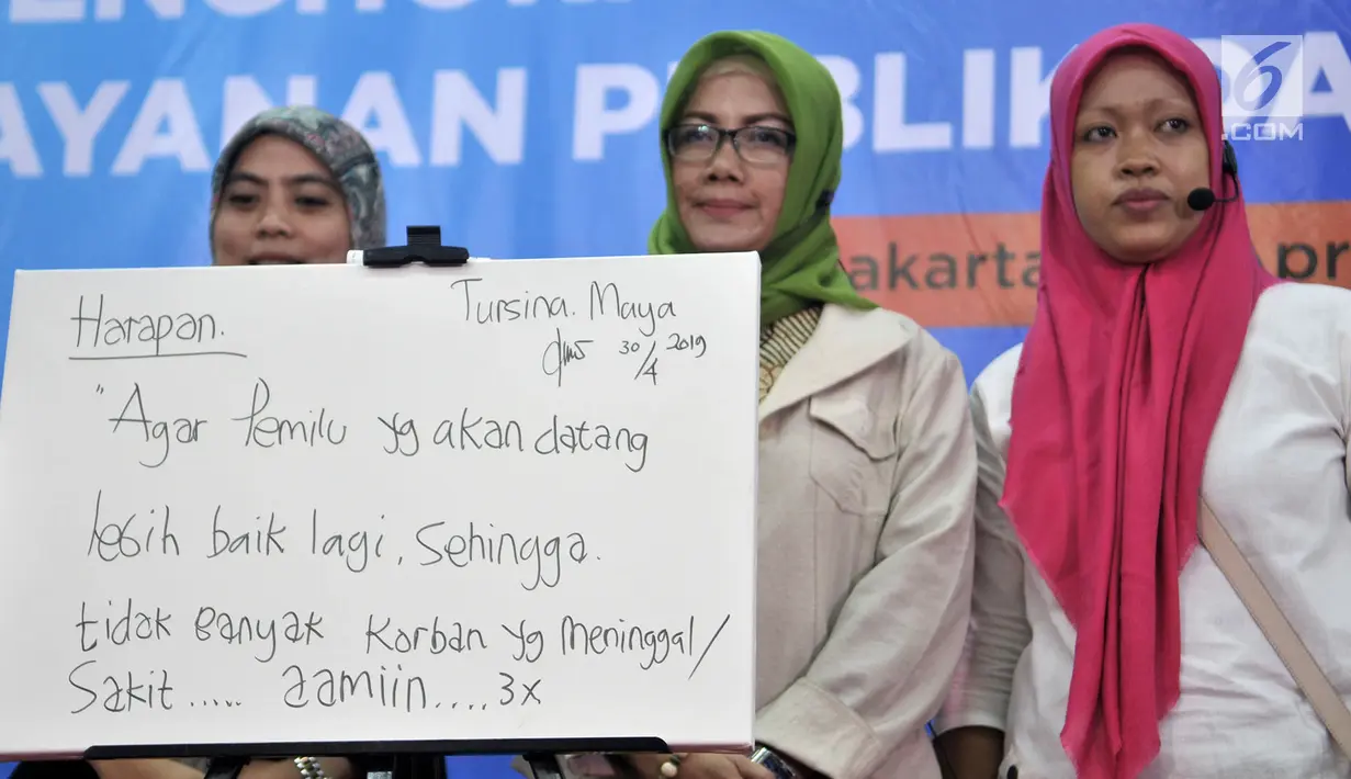 Istri almarhum Ketua KPPS Bekasi Masnun (kanan) dan petugas KPPS Tanjung Priok Tursina Maya (tengah) berfoto di depan kanvas berisi harapan untuk Pemilu yang akan datang saat acara Ngopi Bareng Ombudsman di Ruang Serbaguna Ombudsman RI, Jakarta, Selasa (30/4/2019). (merdeka.com/Iqbal Nugroho)