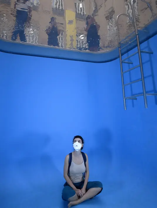 Seorang perempuan berpose untuk foto dengan instalasi "Kolam Renang" karya seniman Argentina, Leandro Erlich di Belo Horizonte, Brasil, Senin (20/9/2021). Karya instalasi Leandro ini membuat orang yang berada dalam kolam renang tidak harus bersusah payah menahan napas. (DOUGLAS MAGNO/AFP)