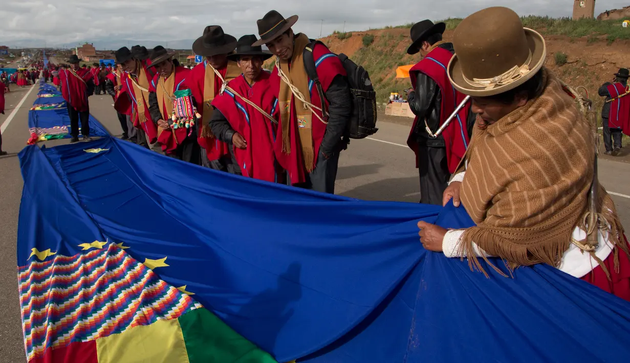 Seorang wanita menyatukan bagian-bagian bendera biru raksasa di jalan raya antara Oruro dan La Paz Bolivia (10/3). Gerakan ini untuk mendukung usaha negara Bolivia untuk mendapatkan akses berdaulat ke laut. (AP Photo / Juan Karita)