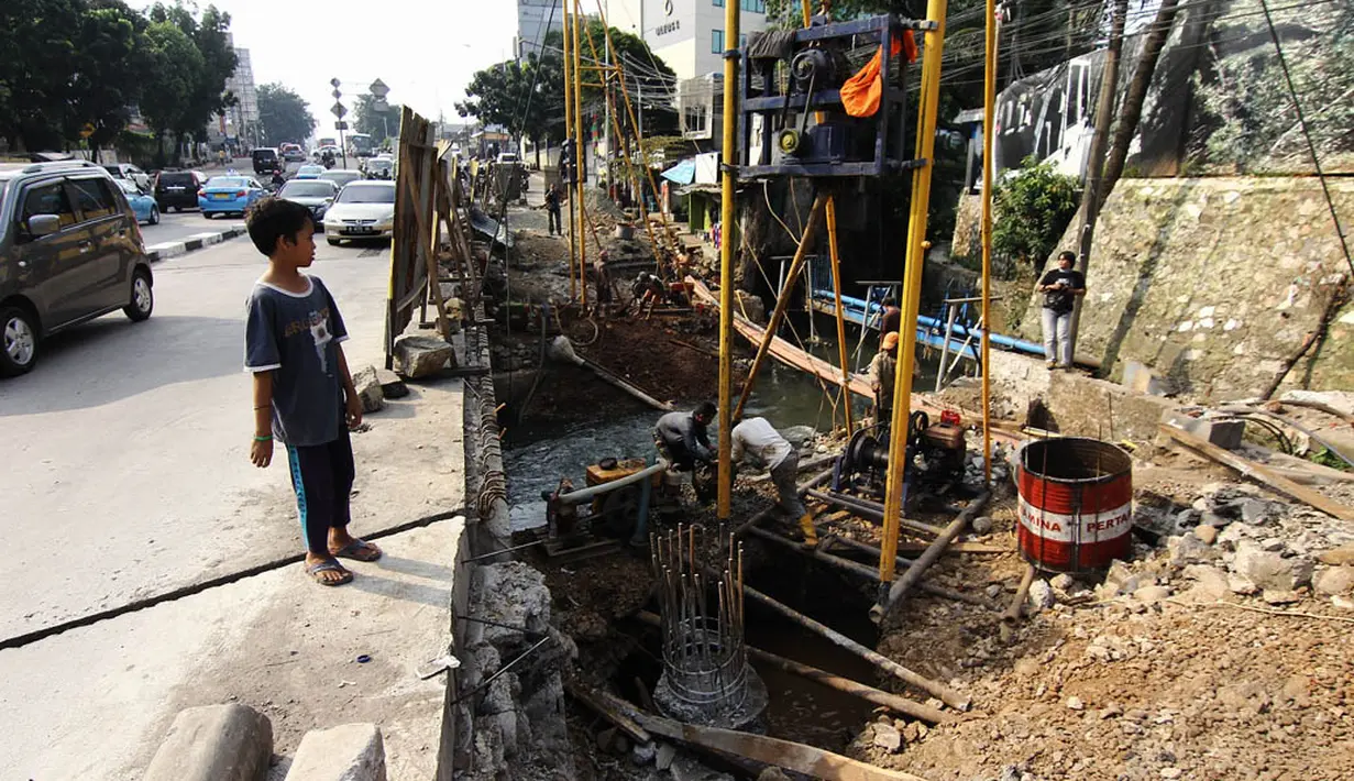 Seorang anak tampak memperhatikan para pekerja menyelesaikan proyek peninggian jembatan Kali Mampang, Jakarta, Kamis (5/6/14). (Liputan6.com/Faizal Fanani)
