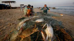 Nelayan Palestina mengenakan masker saat mereka menangkap kepiting di pantai laut Mediterania di Beit Lahyia, Jalur Gaza utara pada 21 September 2020. (AP Photo / Hatem Moussa)