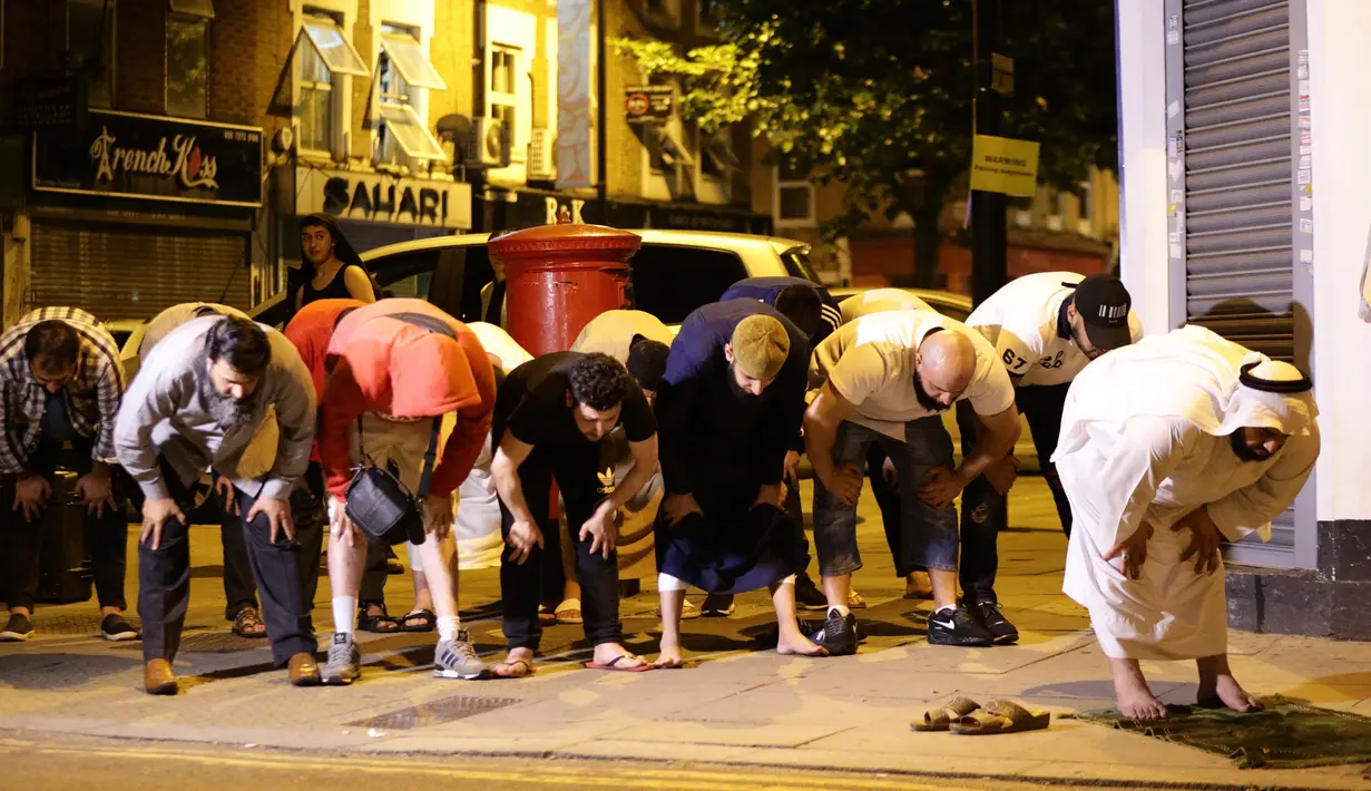 Umat muslim melaksanakan salat di lokasi insiden kendaraan yang menabrak pejalan kaki di Finsbury Park Road, London utara, Senin (19/6). Sebanyak 10 orang dilaporkan terluka akibat peristiwa tersebut, sementara satu orang ditangkap. (Yui Mok/PA via AP)