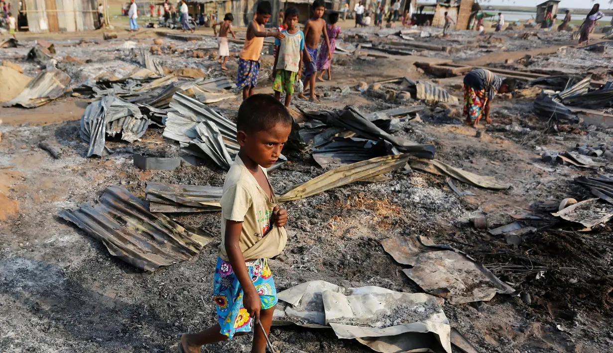 Seorang anak berjalan di antara puing setelah kebakaran kamp pengungsi Muslim Rohingya di Rakhine, Myanmar, Selasa (3/5). Kamp itu tempat penampungan kelompok Rohignya yang tersingkir dari pertikaian dengan kelompok lain pada 2012. (REUTERS/Soe Zeya Tun)