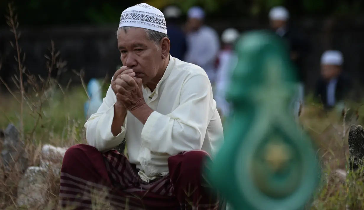 Seorang muslim Thailand berdoa saat menziarahi kuburan kerabat mereka pada perayaan Idul Adha di provinsi Narathiwat, Minggu (11/8/2019). Pada setiap Idul Adha atau menyambut hari besar Islam sebagian warga banyak mendatangi kuburan untuk mendoakan keluarganya. (Madaree TOHLALA/AFP)