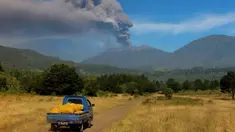 Mobil berjalan saat Gunung Raung mengeluarkan awan panas yang terlihat dari Kabupaten  Bondowoso, Jatim, Minggu (12/7). Gunung Raung terus menunjukkan aktivitas vulkaniknya dan menyebabkan terjadi hujan abu tipis di sejumlah wilayah. (AFP PHOTO/WIDARSHA)