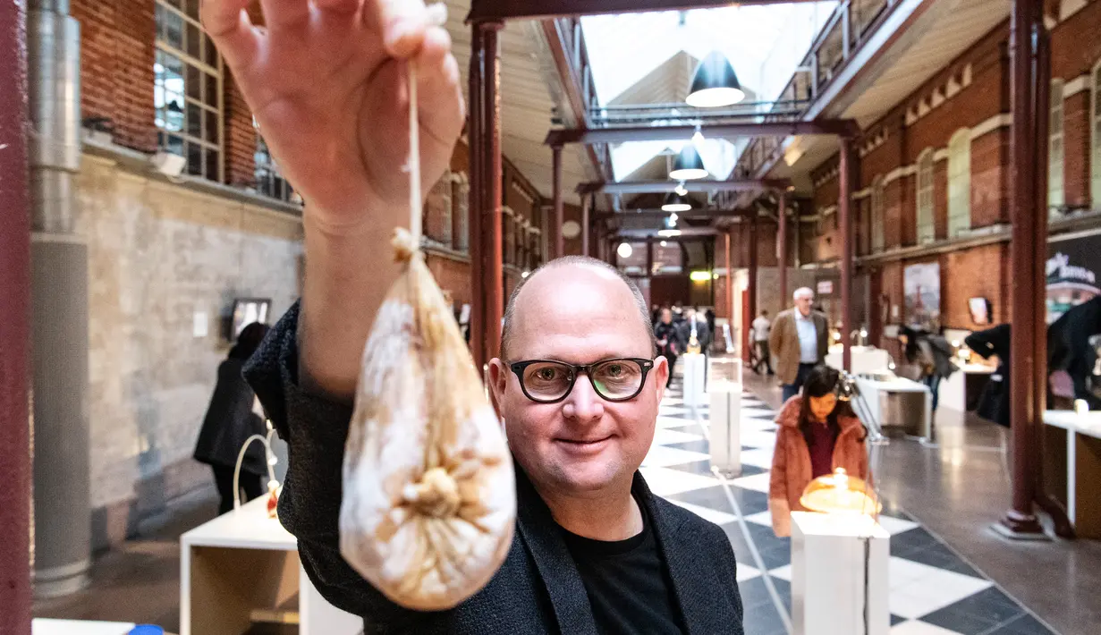 Kurator, Samuel West memegang keju Su Callu yang dibuat menggunakan perut anak kambing yang diisi dengan susu induknya saat Disgusting Food Museum atau Museum Makanan Menjijikan di Malmo, Swedia, 4 November 2018. (Johan NILSSON/TT NEWS AGENCY/AFP)