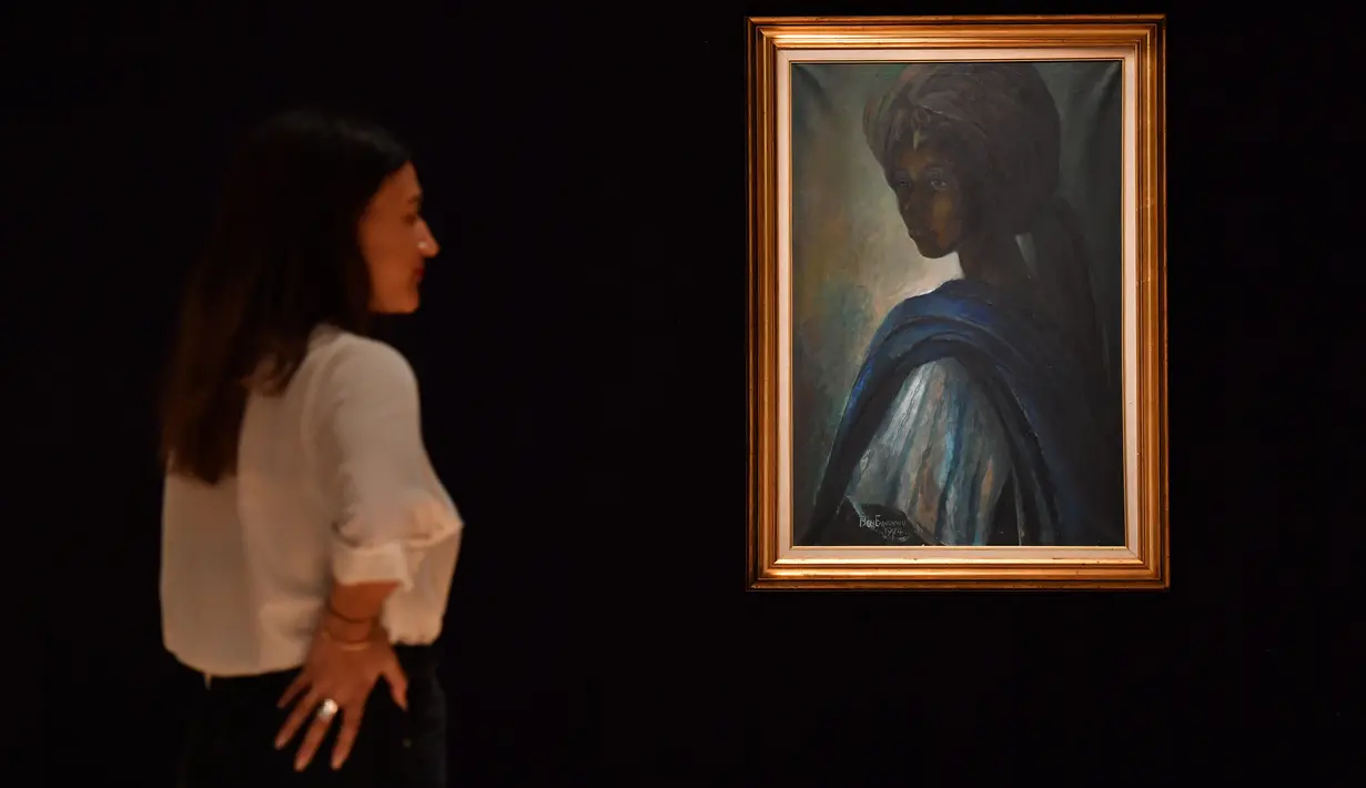 Karyawan rumah lelang Bonhams berdiri dekat lukisan seorang putri Nigeria bernama Tutu di London, Inggris pada 7 Februari 2018. Mona Lisa dari Afrika karya Ben Enwonwu ini merupakan ikon nasional di Nigeria yang dilukis pada 1974. (BEN STANSALL/AFP)
