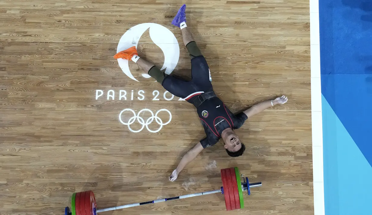 Selebrasi atlet angkat besi Indonesia, Rizki Juniansyah setelah berhasil mengangkat beban seberat 199 kg pada angkatan clean and jerk sekaligus memastikan merebut medali emas saat berlomba pada kelas 73 kg putra cabor angkat besi Olimpiade Paris 2024 di Paris Expo Porte de Versailles, Paris, Kamis (8/8/2024). (AP Photo/Dita Alangkara)