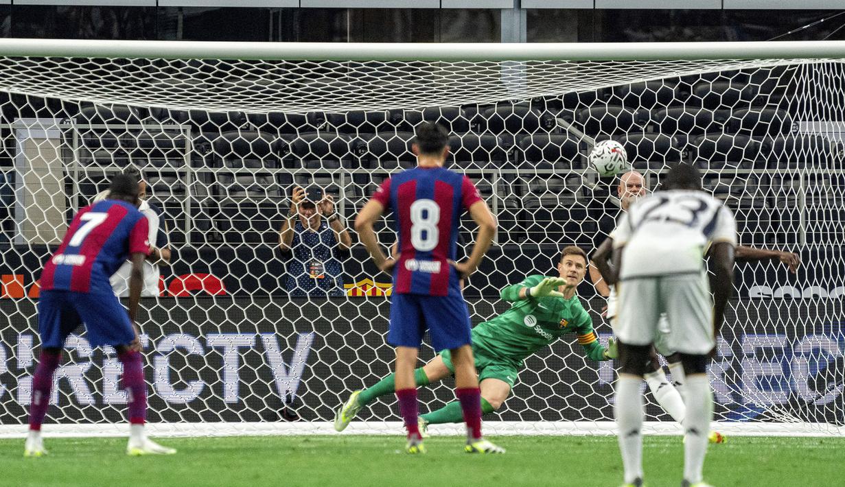 Kiper Barcelona, Marc-Andre ter Stegen berusaha menepis eksekusi penalti striker Real Madrid, Vinicius Junior pada laga pramusim Soccer Champions Tour 2023 di AT&T Stadium, Arlington, Texas, Minggu (30/7/2023) dini hari WIB. (AP Photo/Jeffrey McWhorter)