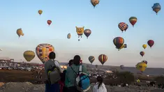 Warga melihat balon udara yang menghiasi langit di Cajititlan, Meksiko, Minggu (7/5).  Festival balon udara ini menjadi tontonan menarik bagi warga sekitar dan wisatawan. (AFP PHOTO / Hector Guerrero)