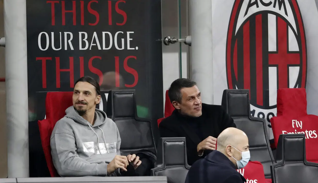 Penyerang AC Milan, Zlatan Ibrahimovic (kiri) dan Paolo Maldini duduk di bangku cadangan sebelum pertandingan melawan Udinese pada lanjutan Liga Serie A Italia di stadion San Siro, di Milan, Italia, Kamis (4/3/2021). AC Milan bermain imbang atas Udinese 1-1. (AP Photo/Antonio Calanni)