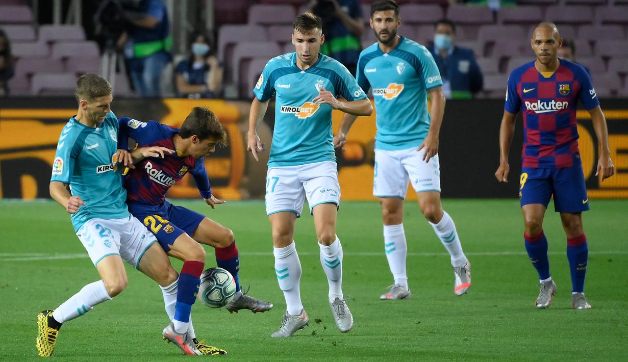 Gelandang Barcelona, Riqui Puig, berebut bola dengan gelandang Osasuna, Darko Brasanac, pada laga lanjutan La Liga pekan ke-37 di Camp Nou, Jumat (17/7/2020) dini hari WIB. Barcelona kalah 1-2 atas Osasuna. (AFP/Lluis Gene)