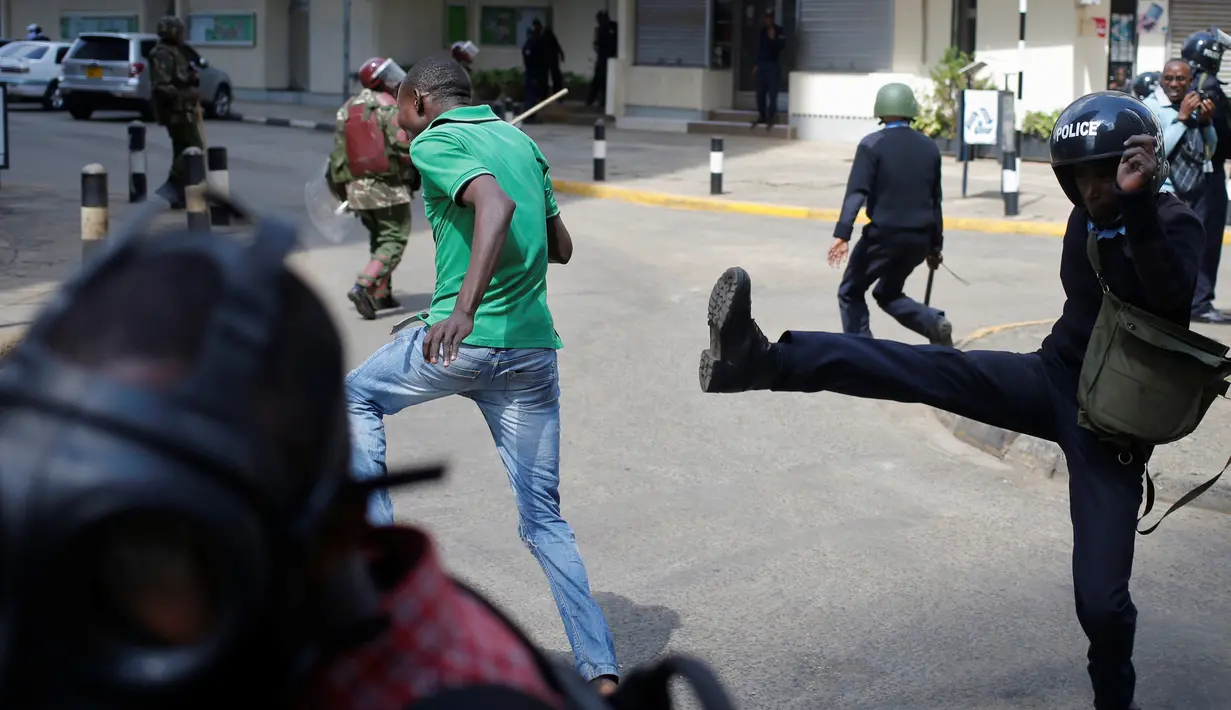 Polisi berusaha menendang demonstran saat bentrokan di Nairobi, Kenya (16/5). Demonstran menuntut pembubaran otoritas pemilu karena adanya dugaan korupsi. (REUTERS/Goran (REUTERS/Goran Tomasevic)