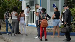 Orang-orang menggunakan ponsel mereka untuk terhubung ke internet melalui WiFi di sebuah taman di Havana, Rabu (5/12). Kuba merupakan salah satu negara terakhir di dunia yang masih belum menerapkan internet mobil. (YAMIL LAGE/AFP)