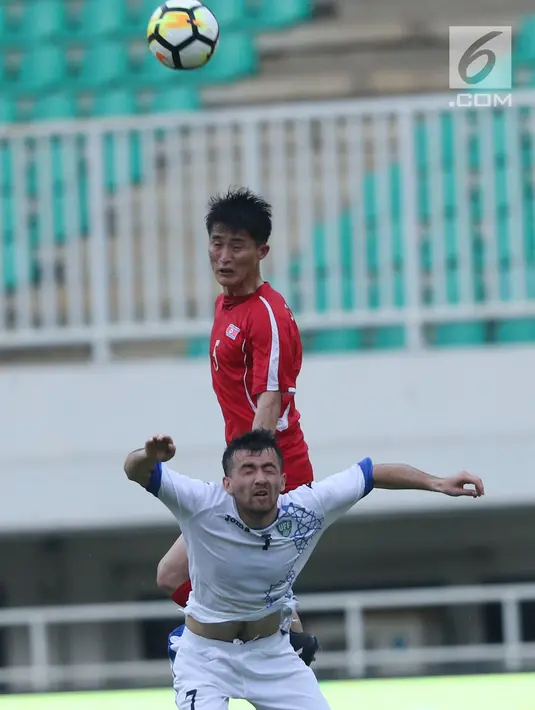 Gelandang Korea Utara, Jon Se Gye (atas) berebut bola dengan pemain Uzbekistan, Tukhtasinov Nurilio pada laga perdana PSSI Anniversary 2018 di Stadion Pakansari, Kab Bogor, Jumat (27/4). Laga berakhir imbang 2-2. (Liputan6.com/Helmi Fithriansyah)