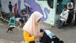 Warga menyelesaikan pembuatan batik tulis saat pelaksanaan kegiatan mural Raincity Strike #8 di Kampung Batik Cibuluh, Bogor, Minggu (22/11/2020). Kegiatan seni mural ini melibatkan puluhan seniman mural se-Jabodetabek di kampung batik. (merdeka.com/Arie Basuki)