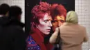 Calon penumpang melihat instalasi seni yang memajang gambar David Bowie terlihat di stasiun kereta bawah tanah Broadway-Lafayette, New York City, 19 April 2018. Seperti diketahui, David Bowie pindah ke New York tahun 1990-an. (ANGELA WEISS/AFP)