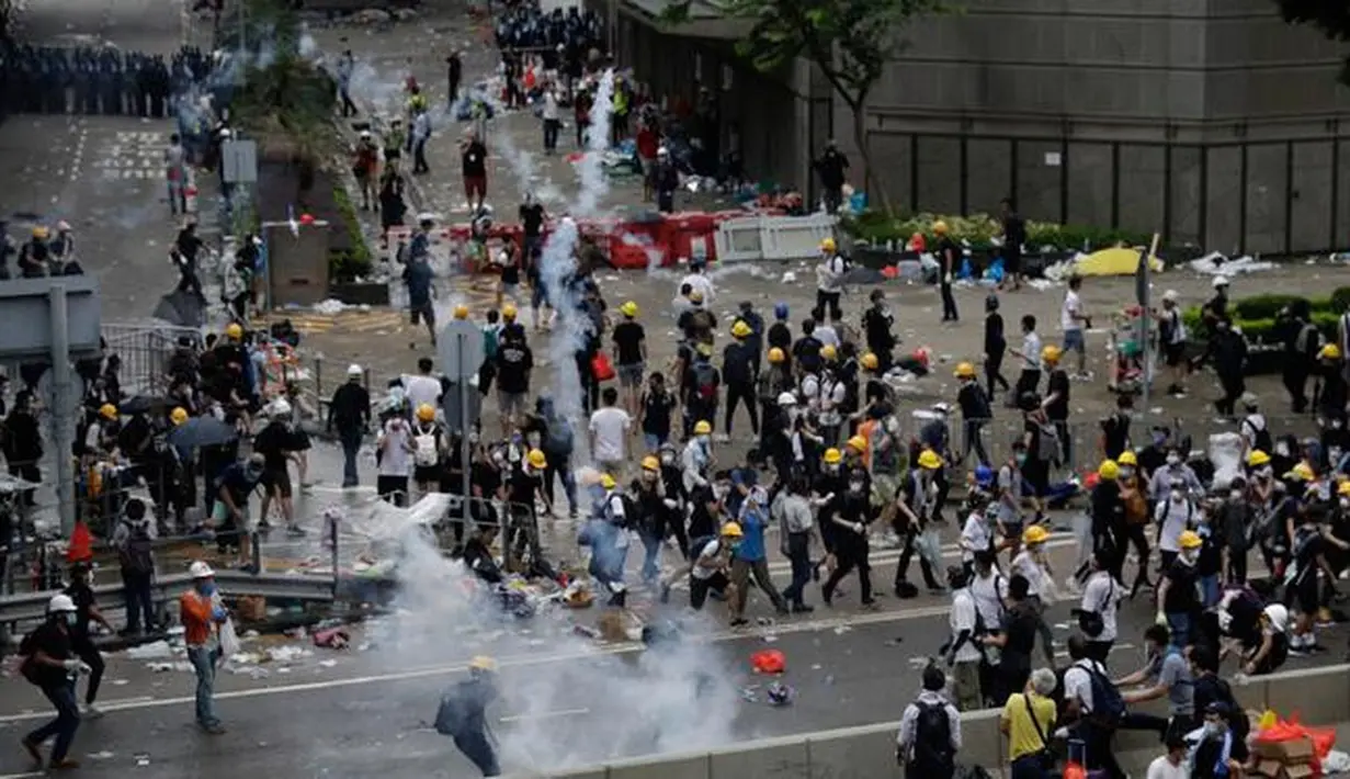 Pengunjuk rasa menghindari gas air mata yang ditembakan oleh polisi anti huru hara di luar gedung Dewan Legislatif, Hong Kong, Rabu (12/6/2019). Polisi Hong Kong telah menggunakan gas air mata ke arah ribuan demonstran yang menentang RUU ekstradisi yang sangat kontroversial. (AP Photo/Vincent Yu)