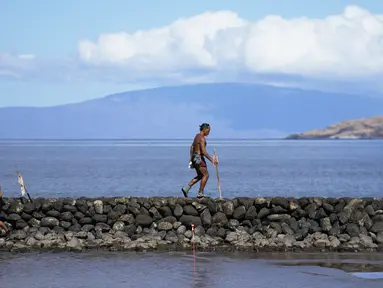 Vicente Ruboi berjalan setelah kebakaran hutan yang melanda Maui di sepanjang tembok laut, di Kihei, Hawaii,  Selasa, 15 Agustus 2023. (AP Photo/Rick Bowmer)