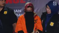 Tersangka kasus penipuan calon jemaah umroh, Kiki Hasibuan menunduk saat diperlihatkan polisi di Bareskrim Mabes Polri, Jakarta, Selasa (22/8). Hingga kini, polisi telah menetapkan tiga tersangka kasus tersebut. (Liputan6.com/Helmi Fithriansyah)