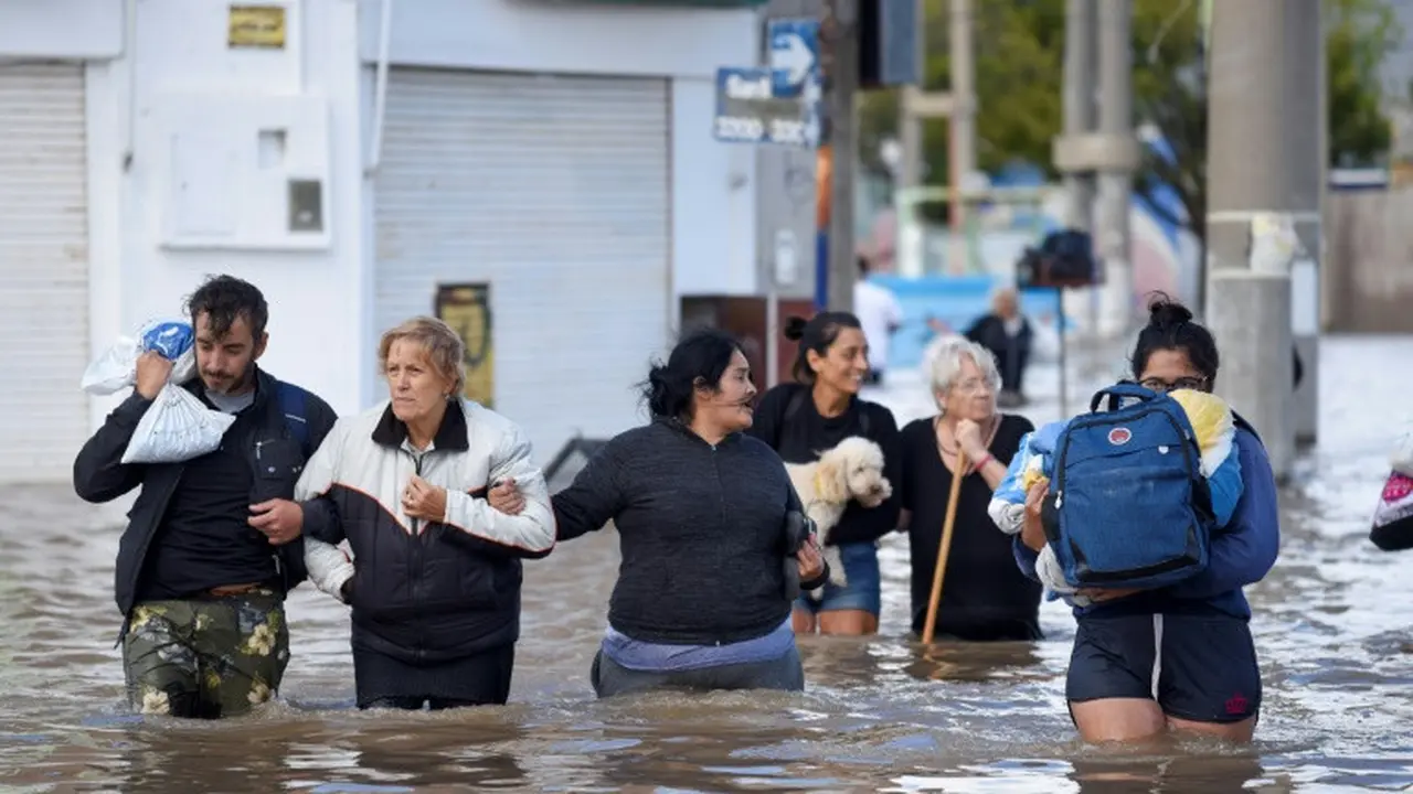 Orang-orang berjalan melewati banjir di Bahia Blanca, Argentina pada 8 Maret 2025 (PABLO PRESTI/AFP)