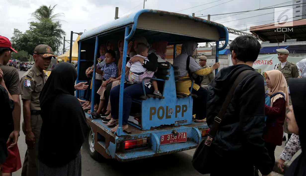 Warga menaiki mobil Satpol PP menelusuri Pasar Tanah Abang di jalan Jatibaru Raya, Jakarta, Selasa (30/1). Layanan jasa angkut dari Satpol PP ini diberikan lantaran bus TransJakarta Tanah Abang Explorer. (Liputan6.com/Gempur M Surya)