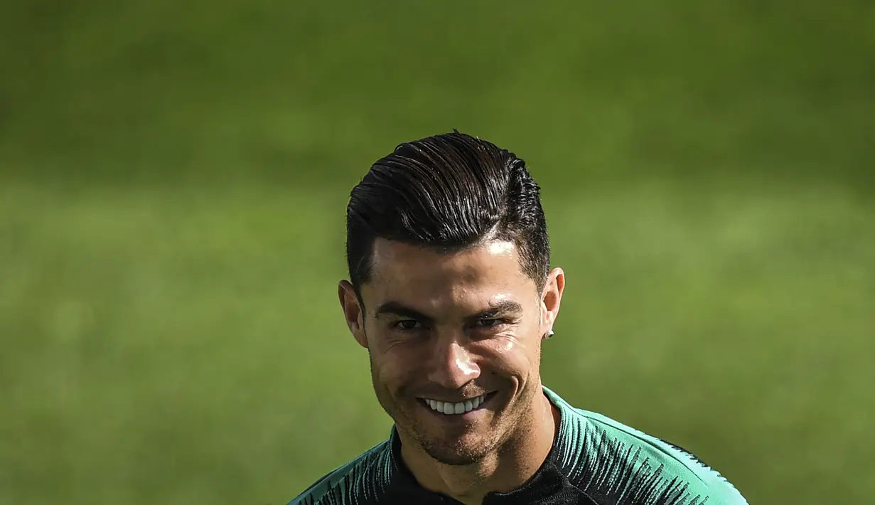 Penyerang Portugal, Cristiano Ronaldo tersenyum selama sesi pelatihan tim di stadion Algarve di Faro (13/11/2019). Portugal akan bertanding melawan Lithuania pada Grup B Kualifikasi Piala Eropa 2020 di Estádio Algarve. (AFP Photo/Patricia De Melo Moreira)