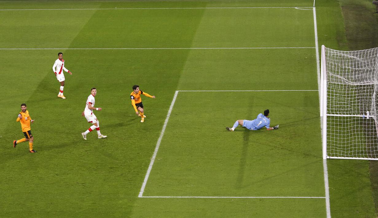 Pemain Wolverhampton Wanderers Pedro Neto (tengah) mencetak gol ke gawang Southampton yang dijaga Alex McCarthy pada pertandingan Liga Primer Inggris di Molineux Stadium, Wolverhampton, Inggris, Senin (23/11/2020). Pertandingan berakhir 1-1. (Michael Steele, Pool via AP)